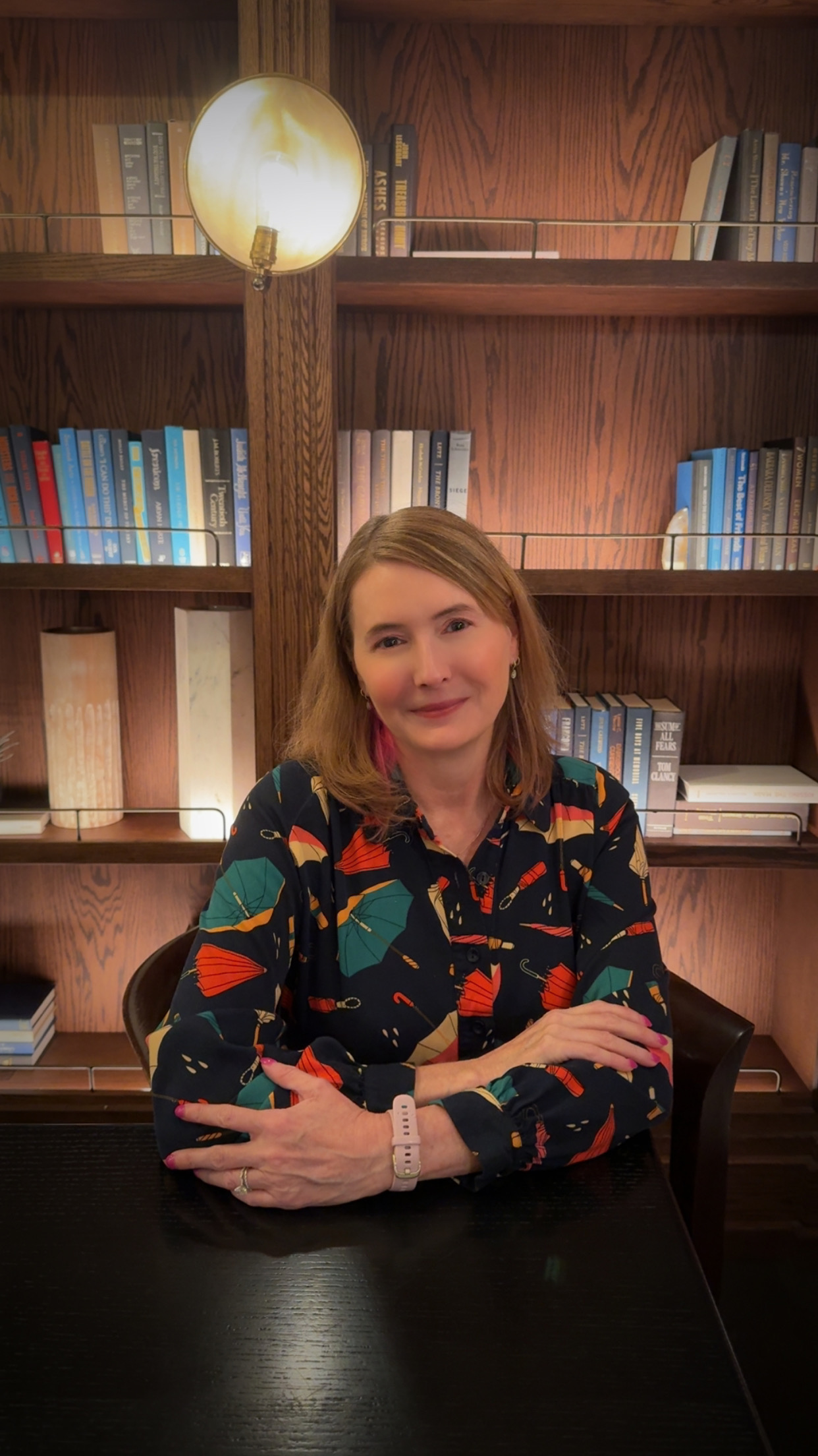 Karen Westing, seated at a table with bookshelves behind her.